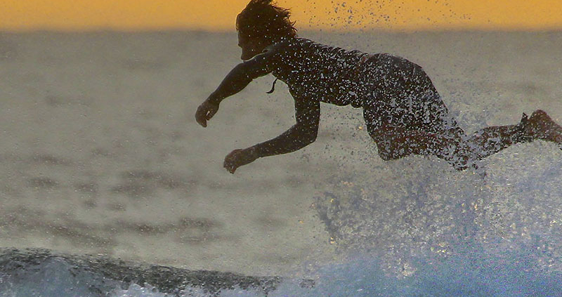 Surf boarder falling off board and into ocean