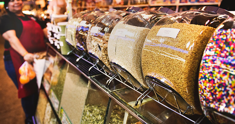 Business owner standing behind row of canisters containing candies and nuts