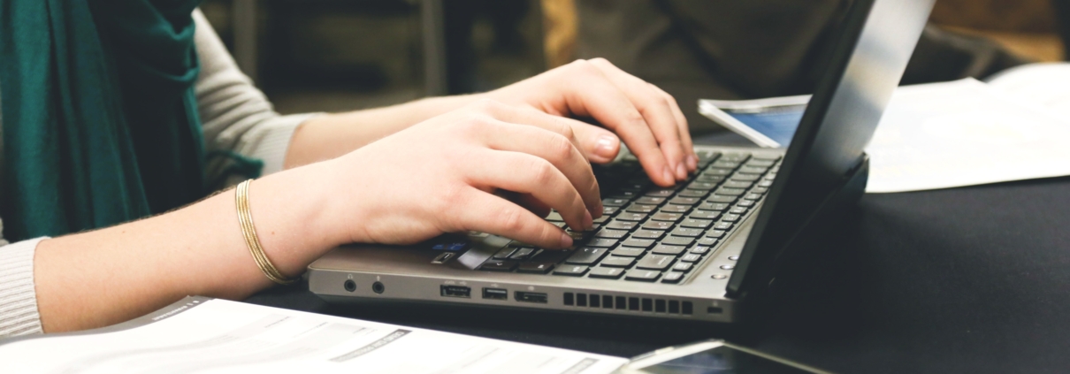 Woman with her hands on a laptop about to write.