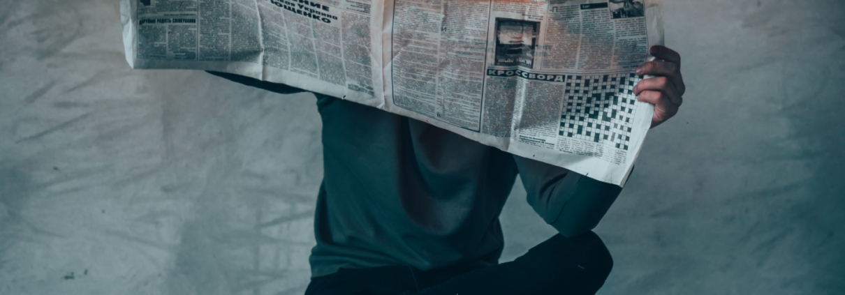 Man sitting on bench holding burning newspaper.