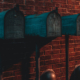 Three green mailboxes against a brick wall in low light