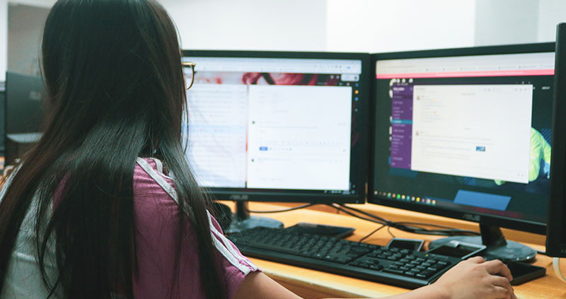 Woman working on two computer screens