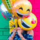 Woman standing in front of colorful wall holding smiley face balloon over her face