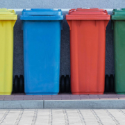 Four colorful recycling bins on a curb