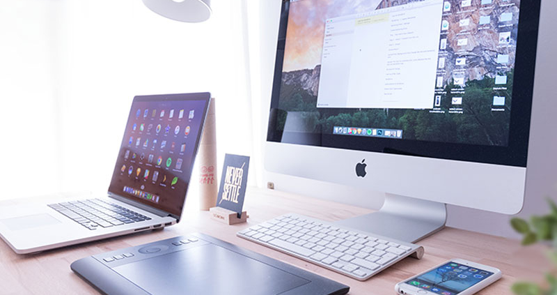 Desk with laptop, desktop, phone, and tablet