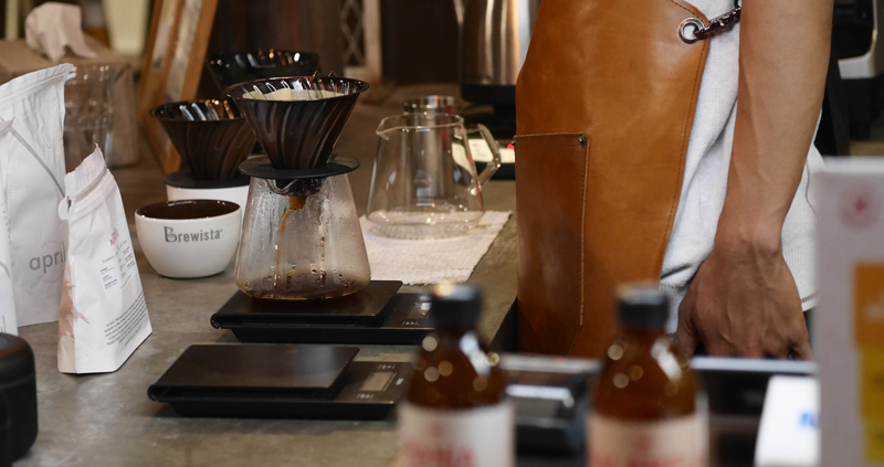 Small business owner in apron making coffee