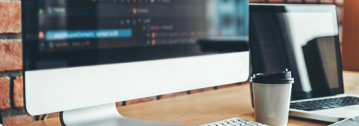 A computer and a coffee cup on the desk of a website designer.