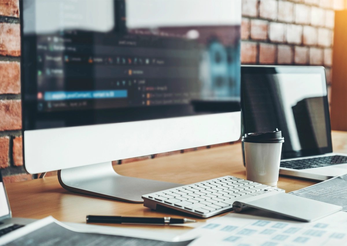 A computer and a coffee cup on the desk of a website designer.