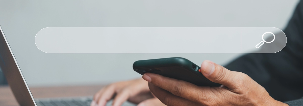 A man searching the internet on a laptop and a cell phone.