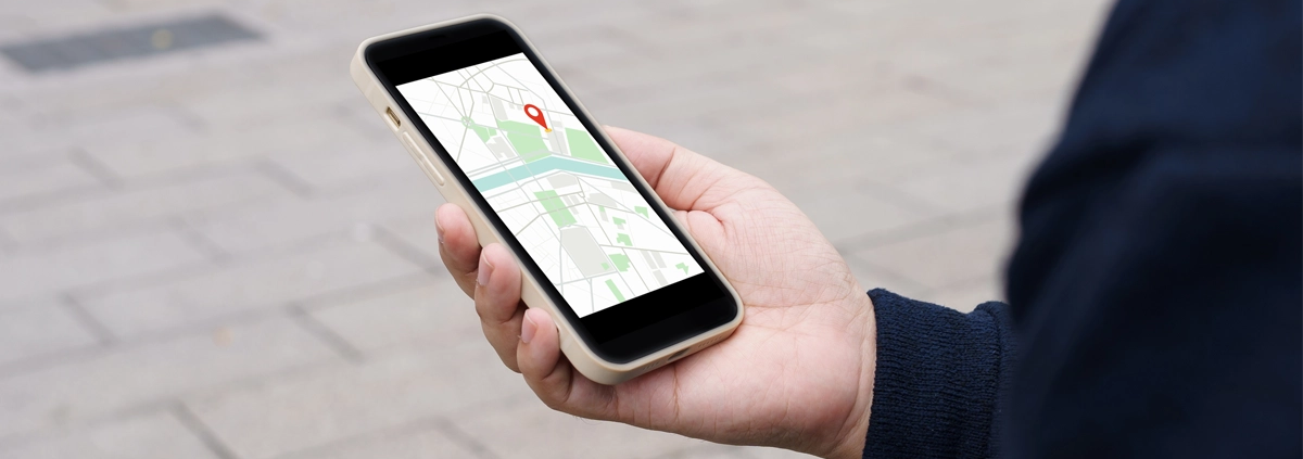 A person holding a cell phone with Google Maps on the screen.