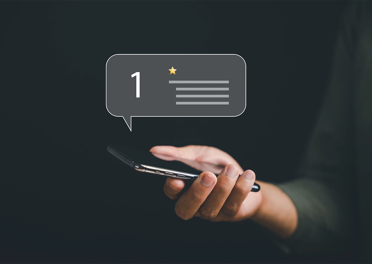 A woman holding a phone depicting a one-star review.